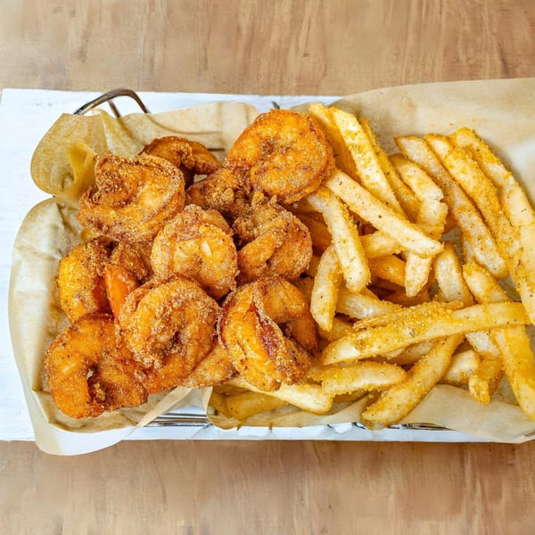 A basket of MiMi's Craft Kitchen's crispy fried shrimp and seasoned french fries.