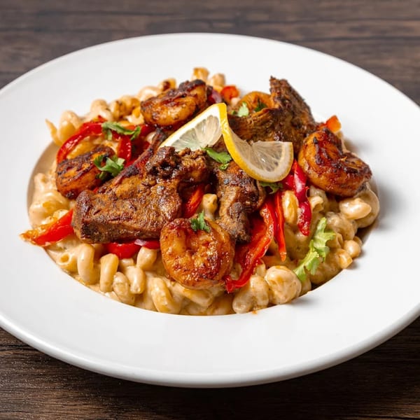 MiMi's Craft Kitchen's American dish with grilled chicken, shrimp, red peppers, and lemon slices over pasta.