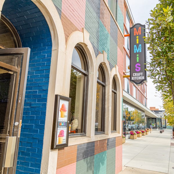MiMi's Craft Kitchen exterior with a colorful brick facade, arched windows, and a prominent sign.